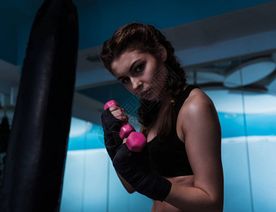 年轻的拳击手女孩用手绷带用粉色哑铃训练女人的力量和美丽她图片