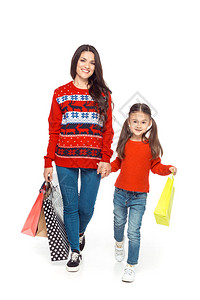 穿着红毛衣装着购物袋的母和女儿在白图片