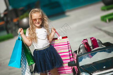 驾驶汽车的小俏丽的女孩驾驶汽车的孩子像个大人提着购物图片