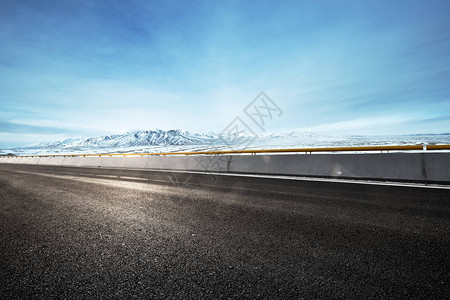 空旷的柏油路和蓝天中的雪山图片