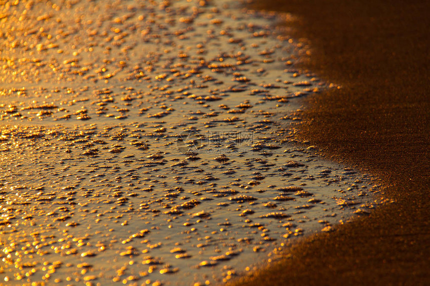 在沙滩和日落太阳反射时的破浪所创图片