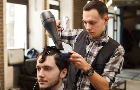 理发师在理发店用吹风机剪头发男图片