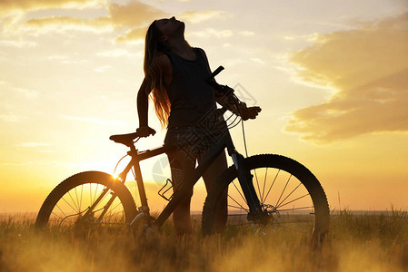 日落时骑自行车的女孩健康的图片