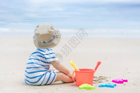 九个月的亚洲小男孩在靠近海洋的沙滩上玩耍图片