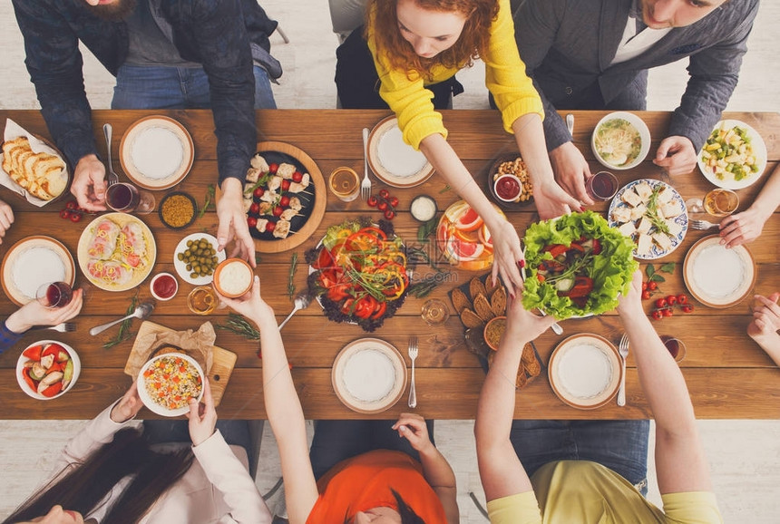 人们在为聚会服务的节日餐桌上吃健康的饭菜朋友们在木桌顶视图上用有机食品庆祝快乐的公司吃午图片