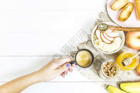 一只雌手在燕麦和吐司旁边拿着一杯咖啡健康早餐顶端视图片