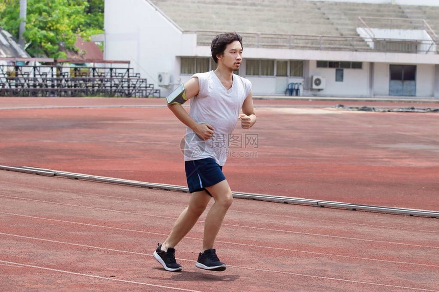 运动员亚洲男子在体育场赛道上跑步图片