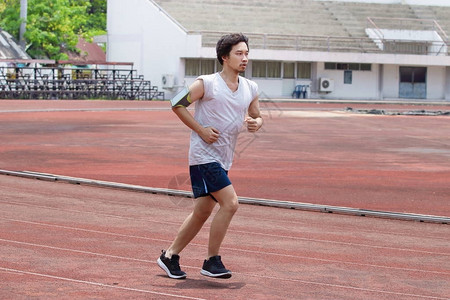 运动员亚洲男子在体育场赛道上跑步图片