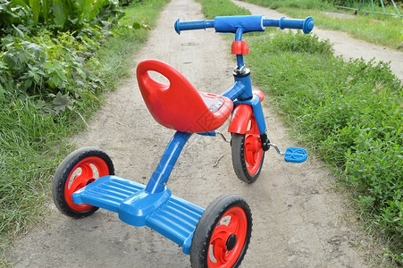 三轮车儿童自行车蓝色和红色的新自行车在花园的路上图片