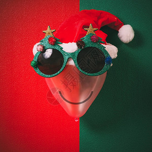 装饰圣诞树和红帽子的圣诞眼镜在绿色背景的气图片