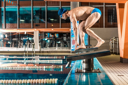 光膀子游泳运动员站在跳板上背景
