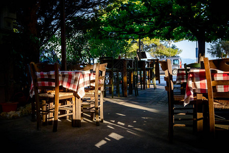希腊典型户外酒馆的椅子和桌椅在晨光图片