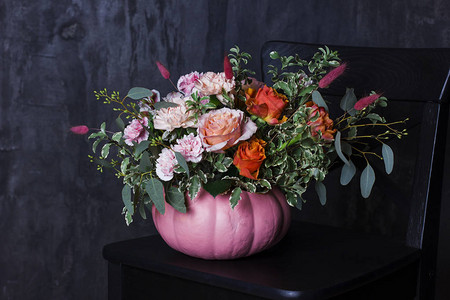 黑色椅子上南瓜花瓶中的秋季花束图片