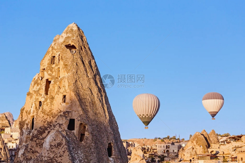 热气球飞越日落时土耳其主要旅游景点之一卡帕多西亚洞穴镇和岩石图片