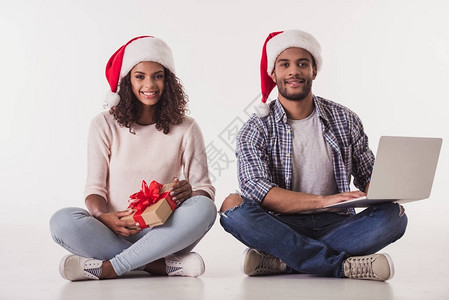 穿着圣诞老人帽子的美黑人夫妇使用笔记本电脑图片