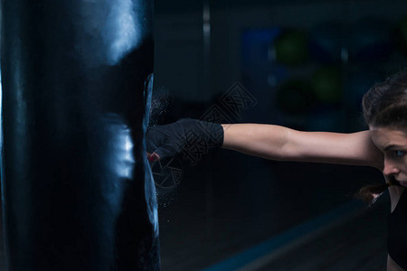 在健身房训练时身着手绷带背着重拳袋的年轻拳击图片