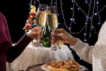 美丽的两个女人拿着香槟庆祝圣诞节和礼品盒在公司聚会和圣诞灯图片