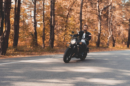 一个长着胡子的年轻人骑着电动摩托车在森林路上图片