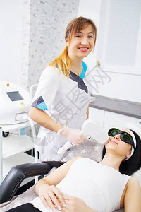 医生美容师在美容院对一位美丽的年轻女子的面部皮肤进行微电流治疗美容和图片