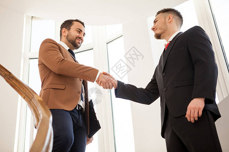 两个微笑着的商人在办公大楼里握手图片