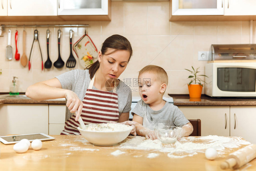 小男孩帮助母亲在轻厨房做圣诞姜饼干图片