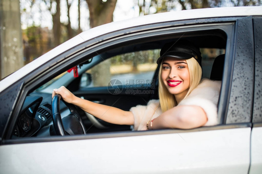 在城市街道上驾驶她的汽车的年轻美女图片
