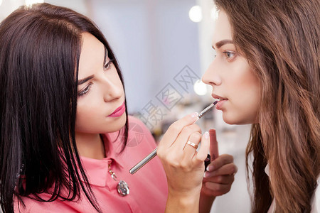 化妆师在美容院给一个漂亮的女孩化妆背景图片