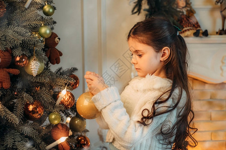悲哀的孩子在晚上装饰圣诞树和玩具图片