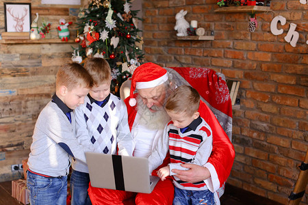 兄弟男孩和妹女孩帮助老圣诞祖父在装饰有高落地灯的房间里选择有趣的节日礼物背景图片