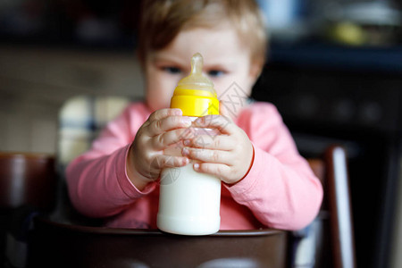 可爱的女婴拿着奶瓶喝配方奶婴儿的第一餐选择地关注孩子的手健康婴儿和奶图片