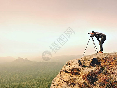 专业摄影师用镜像照相机和三脚架拍摄迷雾风景的照片图片