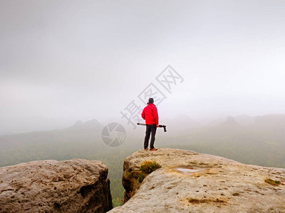 现场专业摄影师在岩石峰顶用相机拍照图片