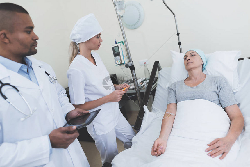医生和护士与一名患有癌症的妇女一起在病房站立图片