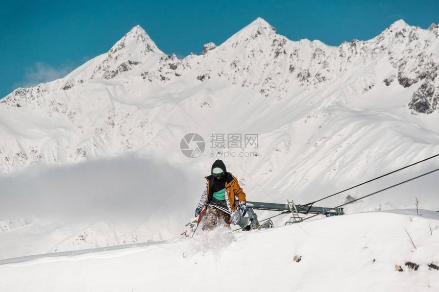 在高山背景下在雪丘上行走的多姿彩运动服装中图片