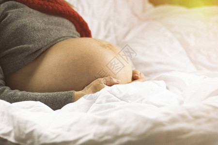 孕妇的腹部和女手在白色背景上图片