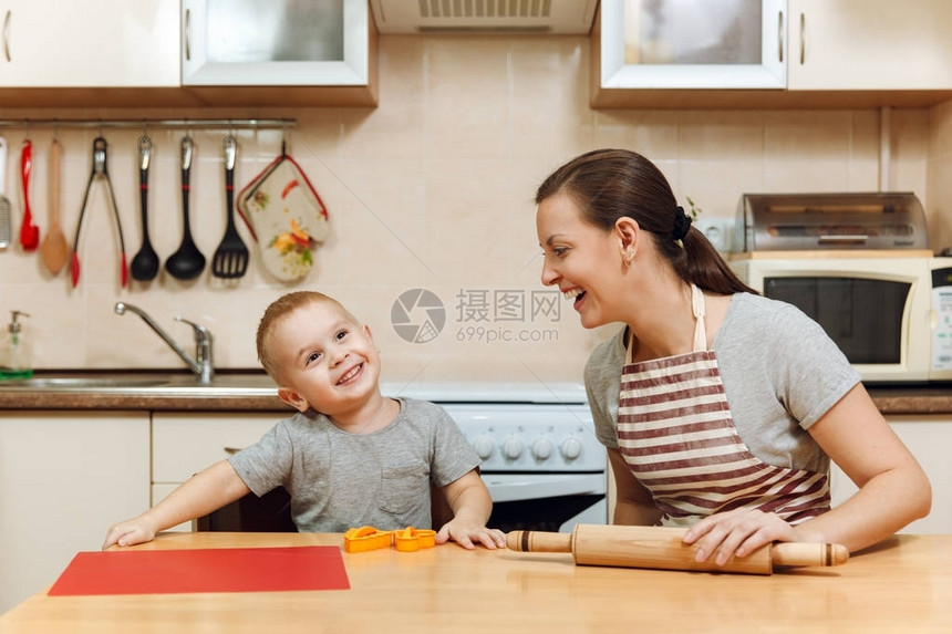 小男孩帮助妈在轻便的厨房里做圣诞姜饼3035岁的幸福家庭妈和23岁的孩子在家里擀面团并切饼干图片