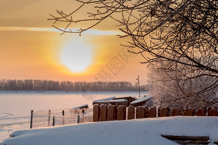 落日笼罩着蓬松的白雪的村庄菜园图片