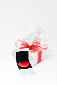 白色珠宝盒中的红色天鹅绒心和白色背景上带有红色丝带图片