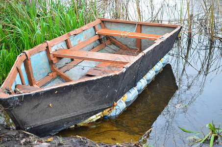 一艘被铁链停泊在河岸上的破旧船图片