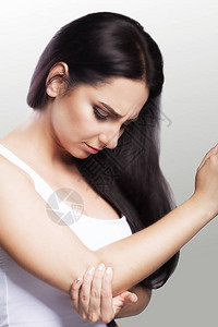 肘部疼痛女孩握着她的手肘手部区域的疼痛感错位断裂健康的概念在图片