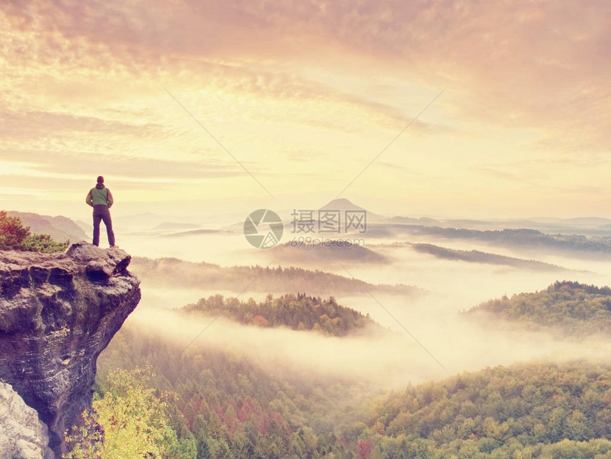 男人在黎明时分停留在岩石峰上图片