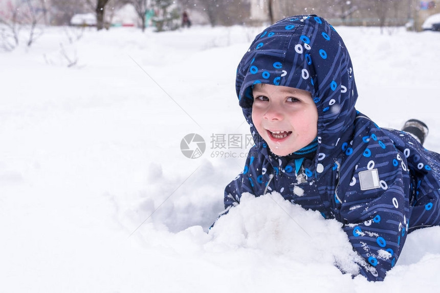 一个小孩从雪地或冰块中向外张望一个孩子在玩雪躺在雪地里微图片