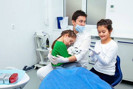 医生向小女孩展示治疗牙齿的程序牙医妇女特别为年轻患者保存平静图片