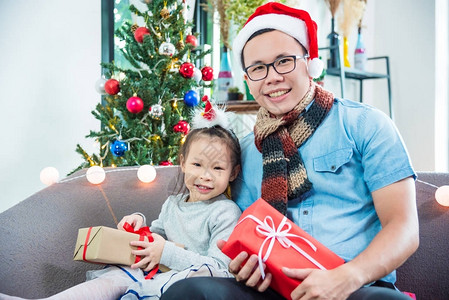 小亚洲女孩在家沙发上和父亲一起开圣诞礼图片