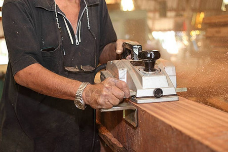 电平板机在木工车间用高级木匠的手刮一块木板有选择的重点和浅图片