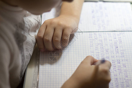 男孩手的特写镜头用铅笔在传统的白色记事本纸上手写英文单词男背景图片