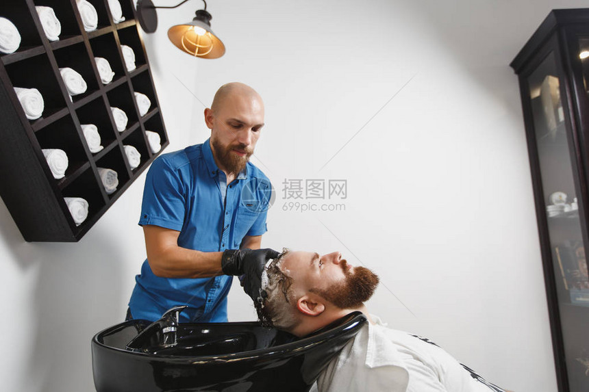 男专业美发师在黑色时尚的洗脸盆中为客户洗头图片