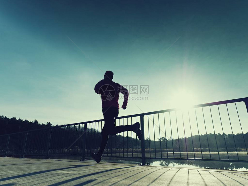 晨跑者穿着高大的黑色紧身裤在桥上锻炼在湖桥上光滑的混凝土地面上进行户外锻炼太阳勾图片