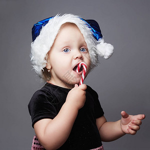 有趣的小圣诞老人女孩用糖果圣诞节快乐的图片