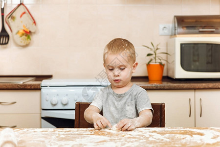 一个小男孩帮助母亲在轻厨房做圣诞姜饼干图片